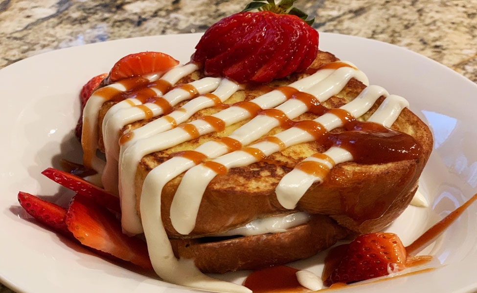 Guava-stuffed French toast with cream cheese drizzle and strawberry garnish